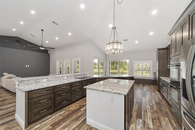 kitchen with light stone counters, dark hardwood / wood-style floors, a spacious island, and lofted ceiling