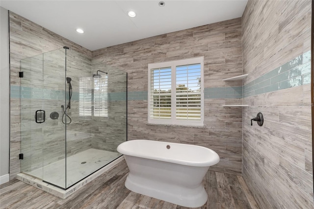 bathroom featuring tile walls, hardwood / wood-style floors, and independent shower and bath