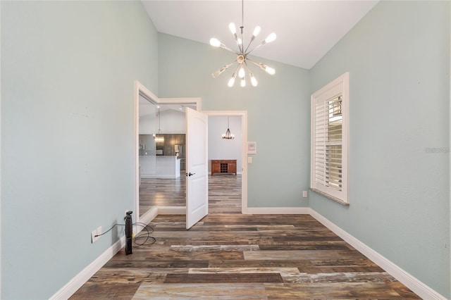 empty room with dark hardwood / wood-style flooring, vaulted ceiling, and a notable chandelier