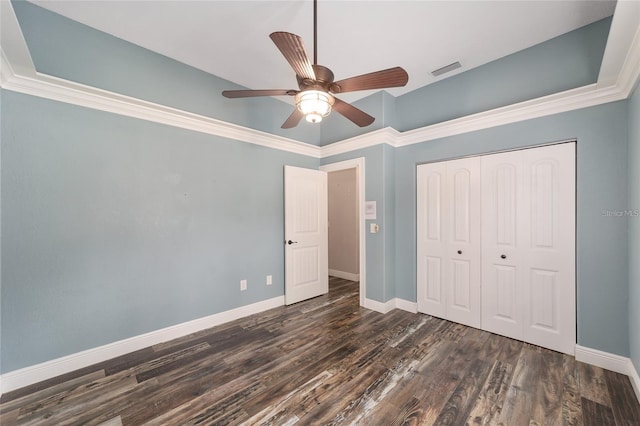 unfurnished bedroom with dark wood-type flooring, ceiling fan, crown molding, and a closet