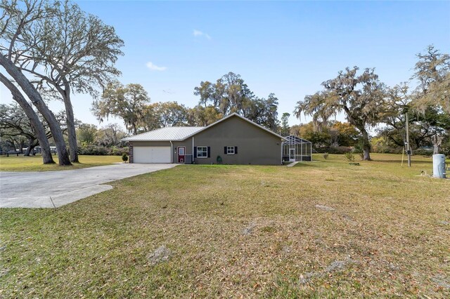 view of side of property featuring a lanai, a garage, and a lawn