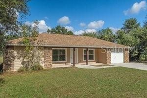 ranch-style home featuring a porch, a front yard, and a garage