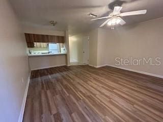 unfurnished living room featuring ceiling fan and dark wood-type flooring