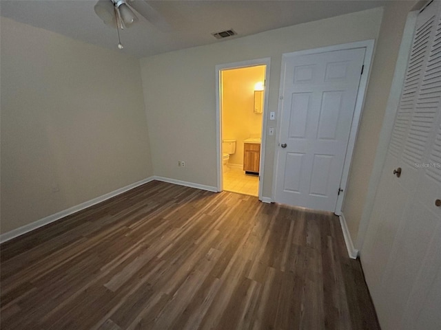 unfurnished bedroom featuring a closet, dark hardwood / wood-style floors, ceiling fan, and connected bathroom