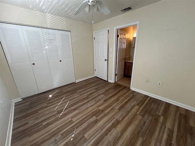 unfurnished bedroom featuring ceiling fan, a closet, ensuite bathroom, and dark hardwood / wood-style floors