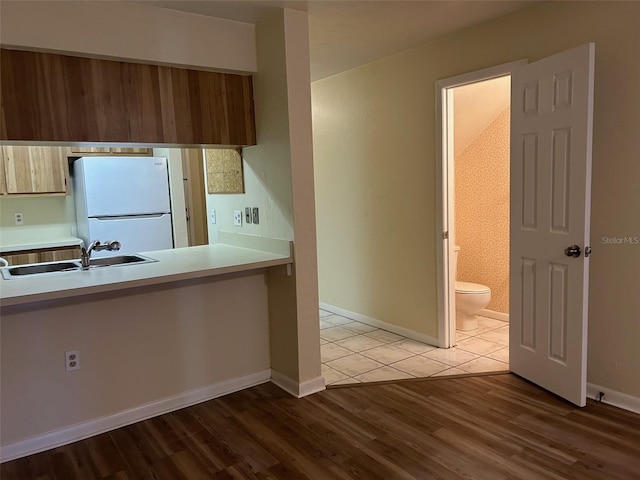 kitchen with hardwood / wood-style floors, white refrigerator, and sink