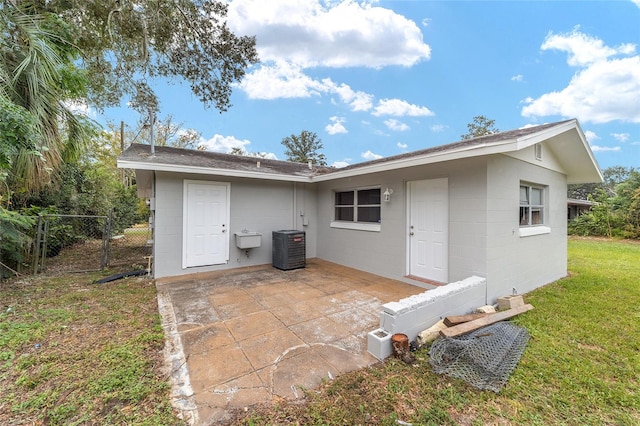 back of property featuring a yard, cooling unit, and a patio