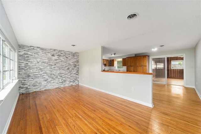 unfurnished living room with light hardwood / wood-style floors and a textured ceiling