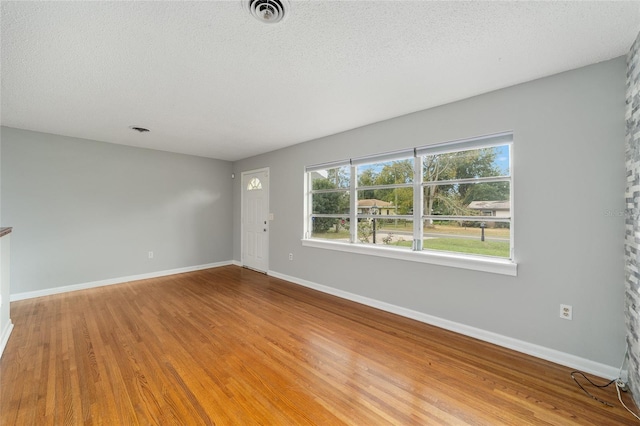 unfurnished room with wood-type flooring and a textured ceiling