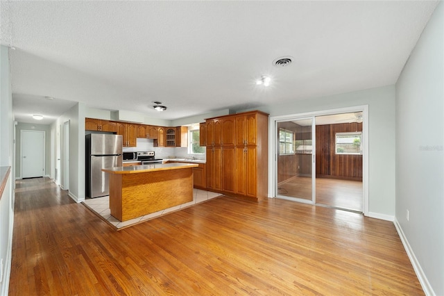 kitchen featuring a textured ceiling, light wood-type flooring, stainless steel appliances, and a kitchen island