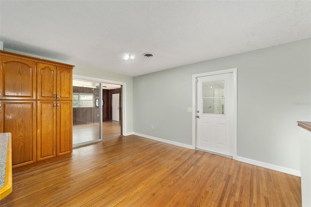 interior space with light wood-type flooring and a textured ceiling