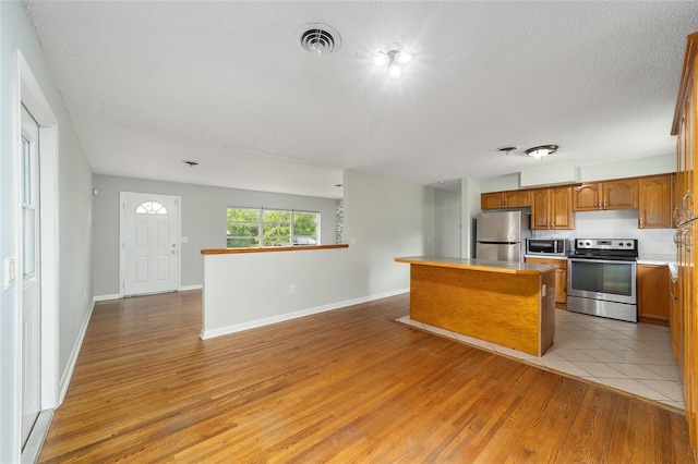 kitchen featuring a center island, light hardwood / wood-style floors, stainless steel appliances, and a textured ceiling