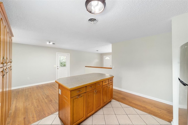 kitchen with a center island, light hardwood / wood-style floors, and a textured ceiling