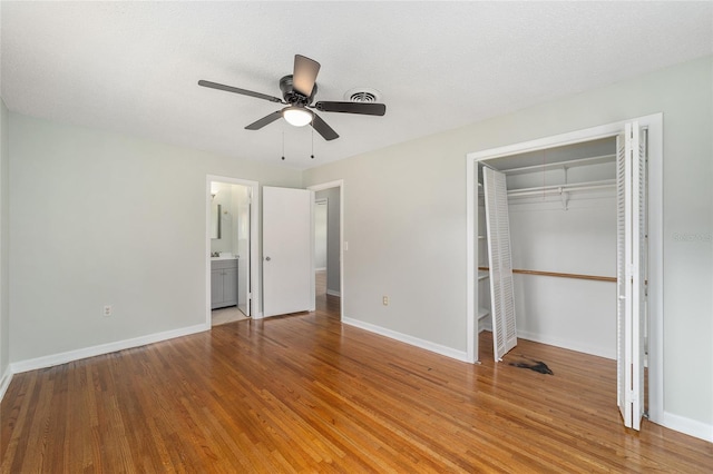 unfurnished bedroom featuring ceiling fan, a closet, ensuite bathroom, and light wood-type flooring