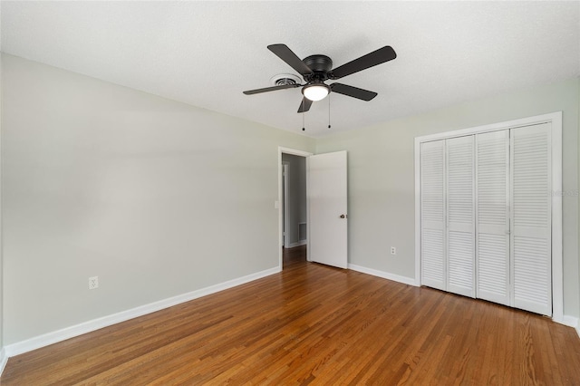 unfurnished bedroom with ceiling fan, wood-type flooring, a textured ceiling, and a closet