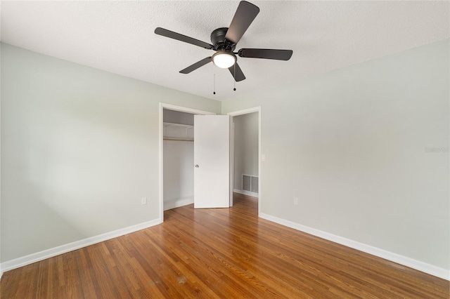 unfurnished bedroom with ceiling fan, wood-type flooring, a textured ceiling, and a closet