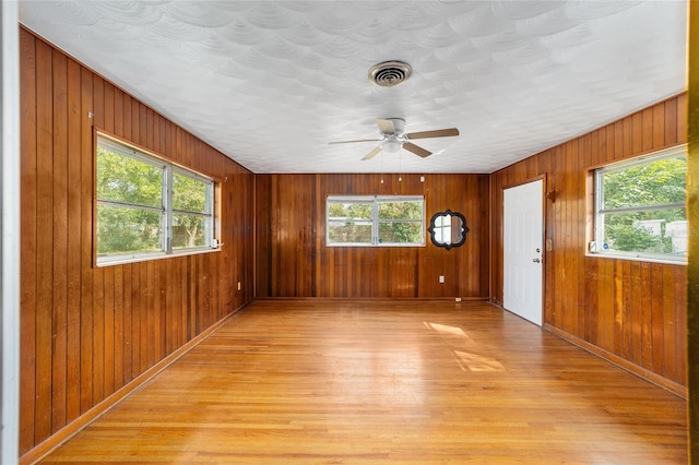 interior space featuring light hardwood / wood-style floors, plenty of natural light, wooden walls, and ceiling fan