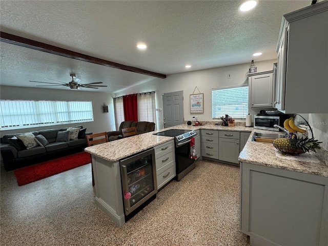 kitchen with sink, a textured ceiling, kitchen peninsula, wine cooler, and appliances with stainless steel finishes