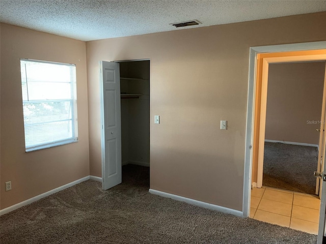 unfurnished bedroom featuring light carpet, a closet, and a textured ceiling