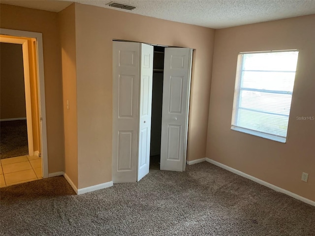 unfurnished bedroom with a closet, carpet, and a textured ceiling