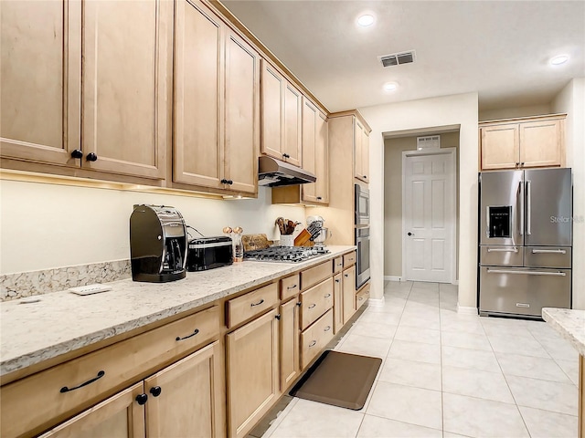 kitchen featuring stainless steel appliances, light brown cabinetry, light tile patterned floors, and light stone counters