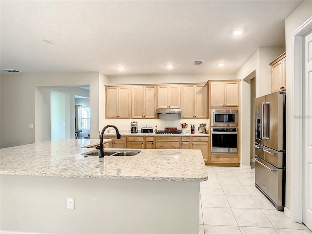 kitchen featuring light tile patterned flooring, sink, light stone counters, appliances with stainless steel finishes, and light brown cabinets