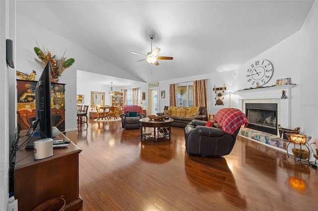 living room with hardwood / wood-style flooring, ceiling fan with notable chandelier, a fireplace, and high vaulted ceiling