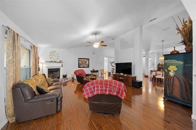 living room featuring ceiling fan, dark hardwood / wood-style flooring, lofted ceiling, and a tiled fireplace