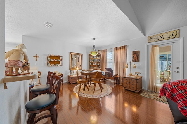 dining area featuring a textured ceiling, hardwood / wood-style flooring, and lofted ceiling