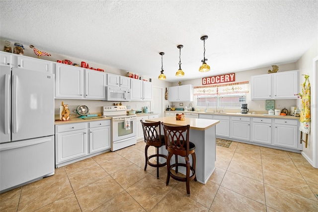 kitchen with a kitchen breakfast bar, white appliances, decorative light fixtures, a center island, and white cabinetry