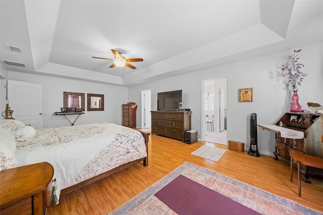 bedroom with a raised ceiling, ceiling fan, and hardwood / wood-style floors