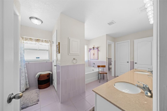 bathroom with tile patterned floors, a washtub, a textured ceiling, vanity, and toilet