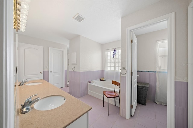 bathroom featuring tile patterned floors, vanity, a tub to relax in, and tile walls