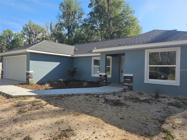 ranch-style home with an attached garage, roof with shingles, and stucco siding