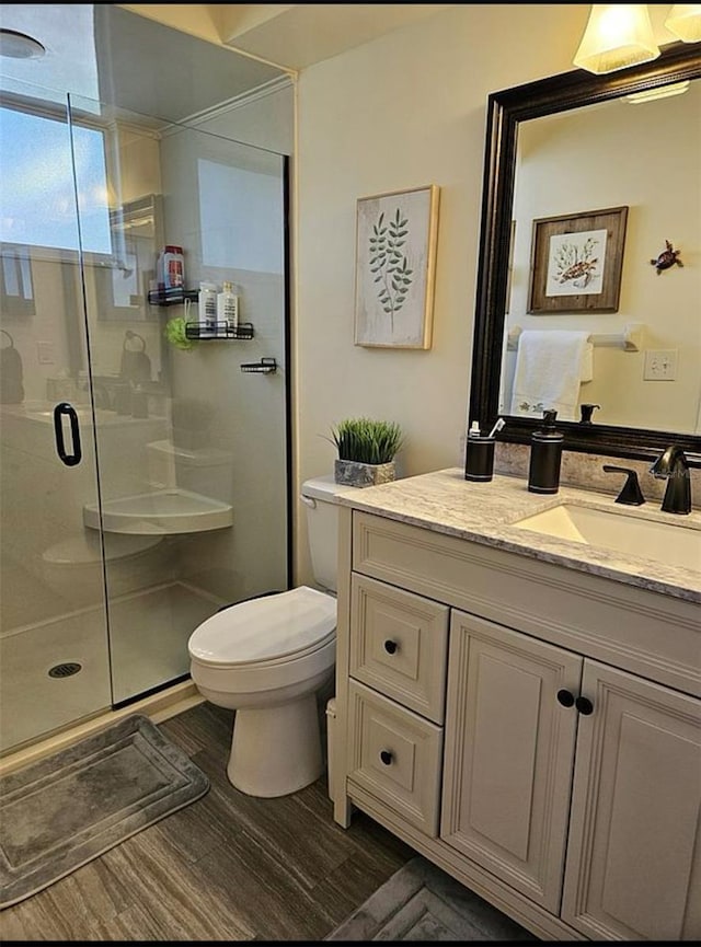 bathroom with walk in shower, vanity, hardwood / wood-style flooring, and toilet