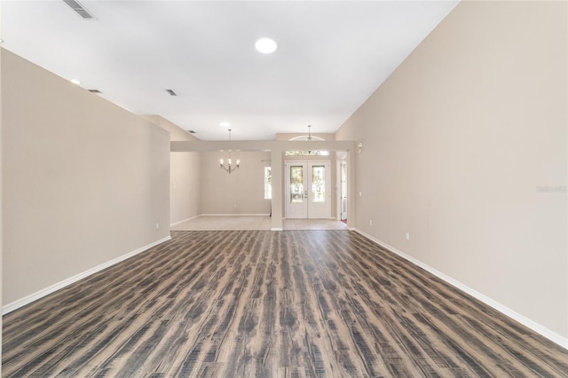 unfurnished living room with french doors, dark wood-type flooring, and a chandelier