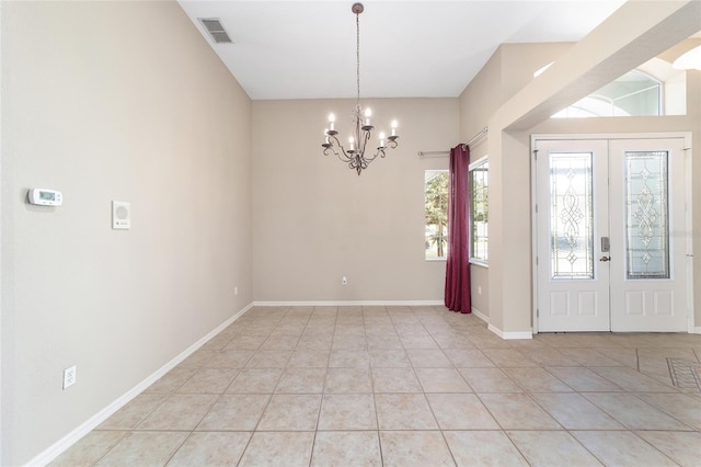 foyer entrance with french doors, light tile patterned floors, and a chandelier