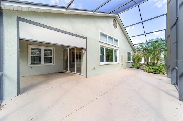 back of property featuring glass enclosure and a patio