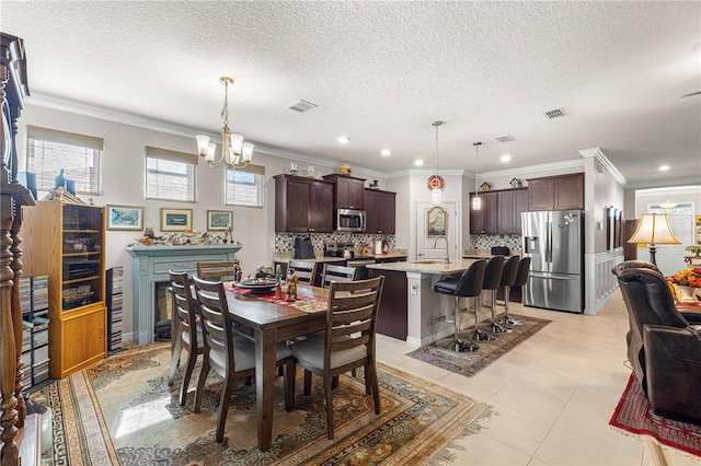 dining area featuring sink, ornamental molding, a textured ceiling, light tile patterned floors, and a chandelier