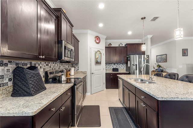 kitchen with appliances with stainless steel finishes, tasteful backsplash, an island with sink, crown molding, and pendant lighting