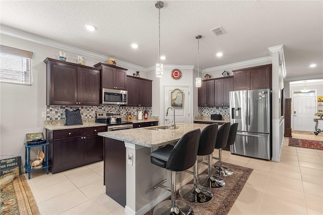 kitchen featuring stainless steel appliances, sink, an island with sink, ornamental molding, and a breakfast bar