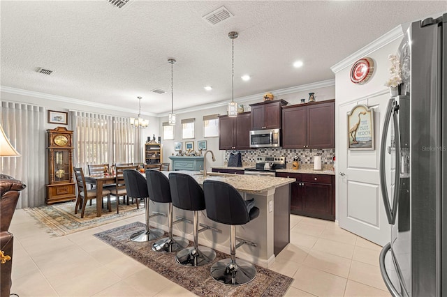 kitchen featuring stainless steel appliances, ornamental molding, a kitchen breakfast bar, a kitchen island with sink, and pendant lighting