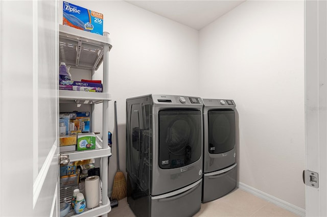 laundry room featuring washing machine and dryer and light tile patterned flooring