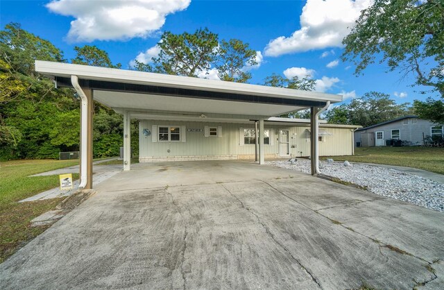 view of parking / parking lot featuring a yard and a carport