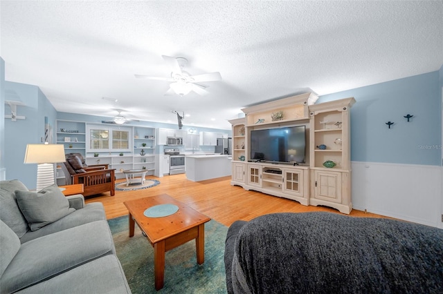 living room featuring a textured ceiling, light hardwood / wood-style flooring, and ceiling fan