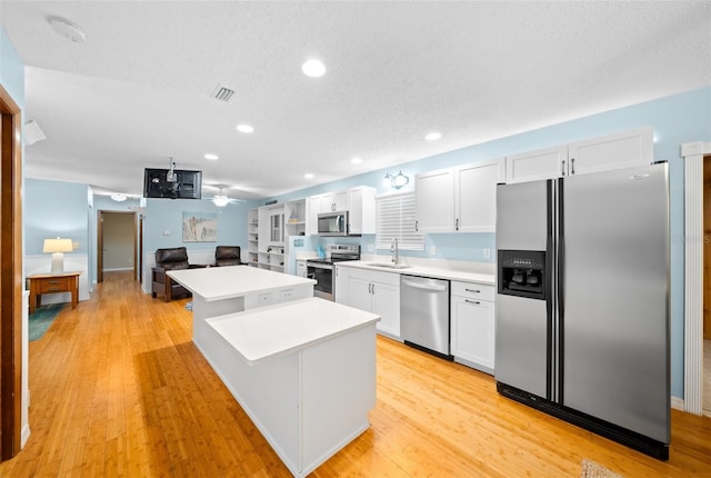 kitchen with a center island, white cabinetry, stainless steel appliances, and light hardwood / wood-style flooring