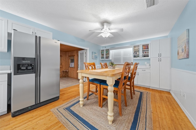 dining area featuring ceiling fan, light hardwood / wood-style flooring, and a textured ceiling