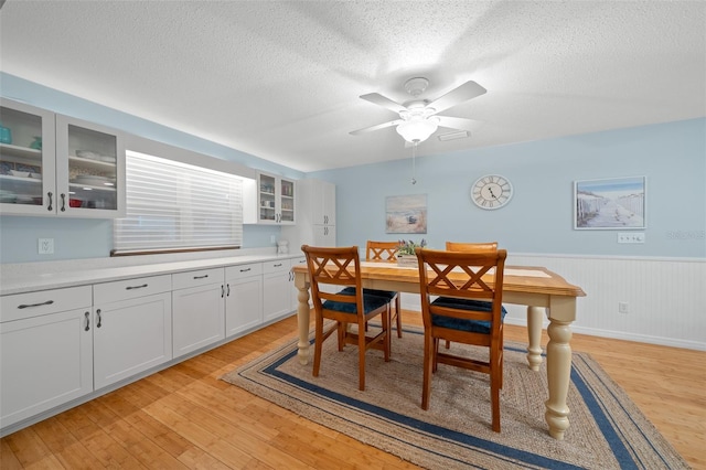 dining space with a textured ceiling, light hardwood / wood-style floors, and ceiling fan