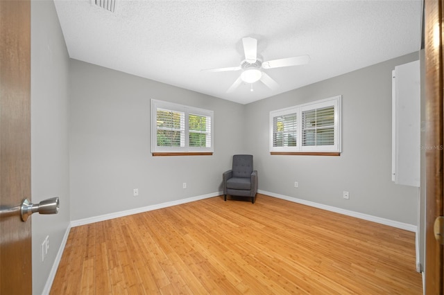 unfurnished room with ceiling fan, light hardwood / wood-style floors, and a textured ceiling