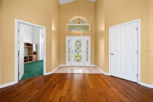 entryway with wood finished floors, a towering ceiling, and baseboards